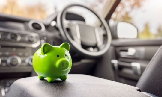 A green piggybank sits on the center console of a car representing 11 tips to save on car insurance.