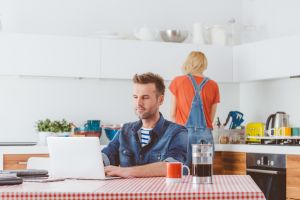 Man working on laptop at home in the kitchen