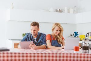 Adult couple using digital tablet and laptop at home