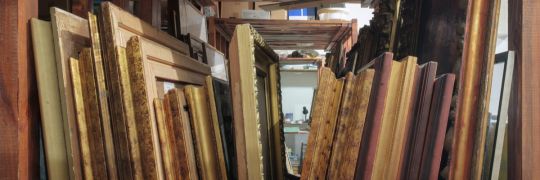 Framed artworks stacked together in storage