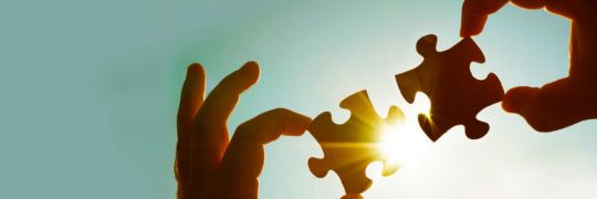 Hands holding two jigsaw pieces