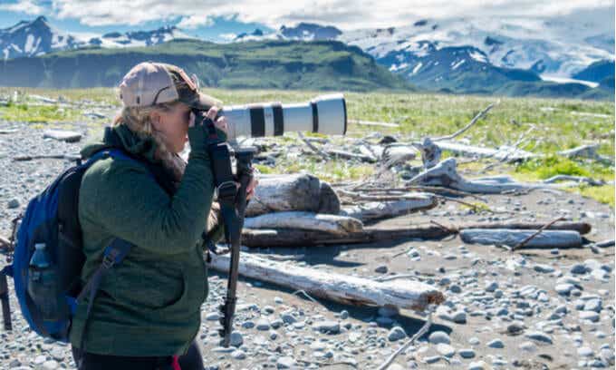 Woman with long-lens camera taking photo of mountains