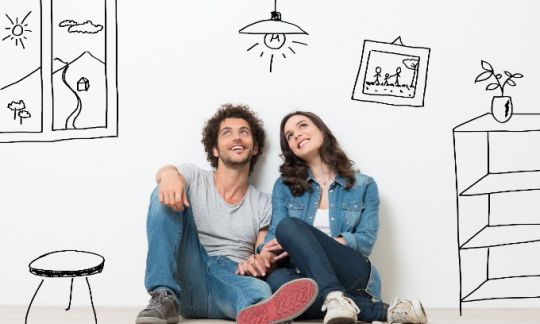 two people sitting in front of a white wall with house items drawn on it