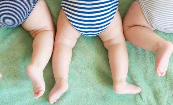 Newborn triplets lie on a stomach on a blanket