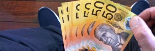 A hand holding a bunch of $50 notes