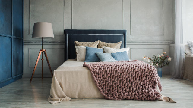 A thick, knitted throw rug on the end of a bed.