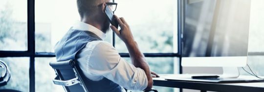 Man sitting at desk talking into a phone