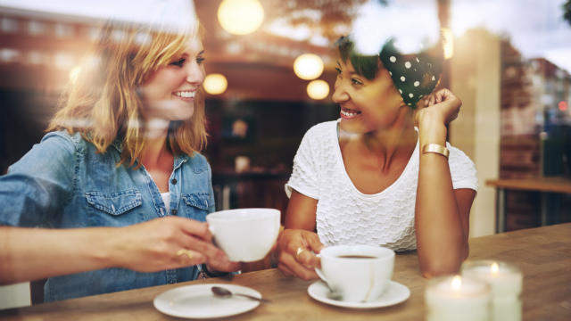 Two women drinking coffee at a cafe.