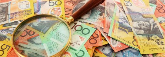 A pile of Australian money with a magnifying glass.
