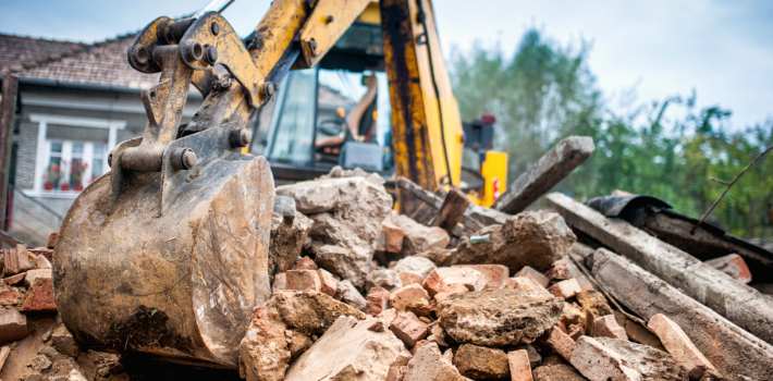 Excavator machine demolishing a house