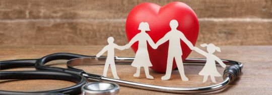 An image of a cutout family in front of a heart, with a stethoscope