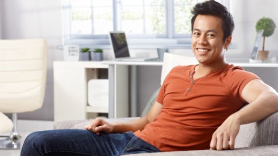 A man sits on a couch inside a nice house