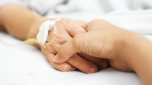 Two people holding hands in a hospital bed