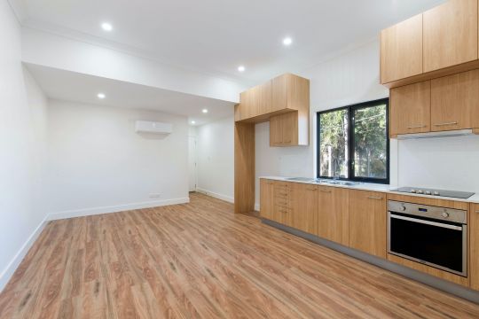 An empty kitchen with wooden floors