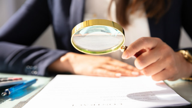 Person looking at paper with magnifying glass
