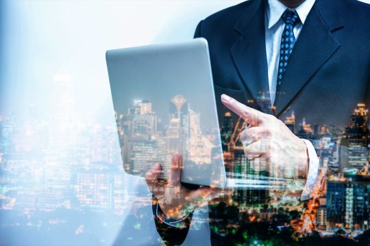 A layered image of a city landscape, man with a laptop and investor graph