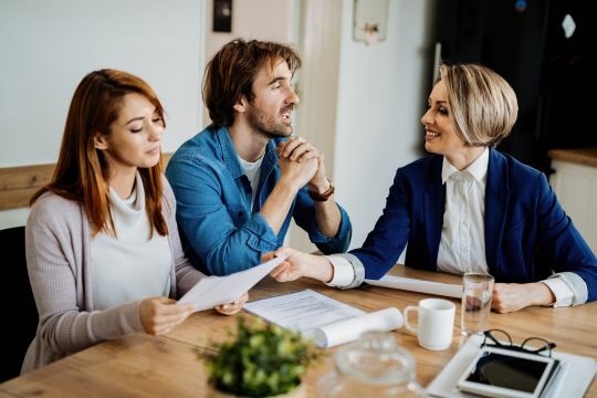 A Young couple sitting at a desk talking with a financial advisor