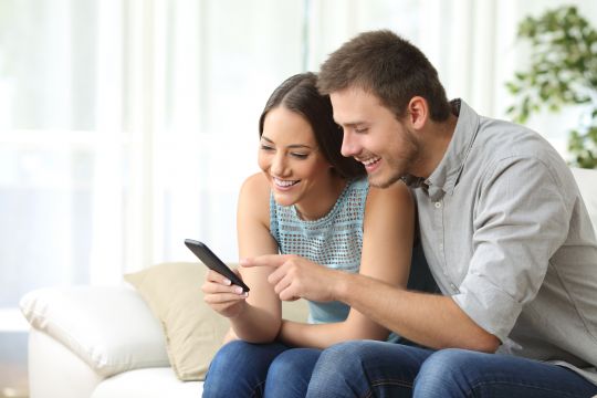 A young couple looking at an app of their phone