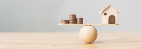 House balancing with coins represents equity