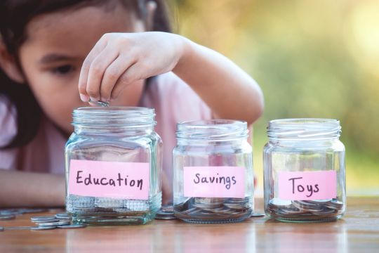 Child adding coins into jars to save