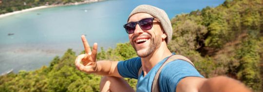 A man taking a selfie on the beach.