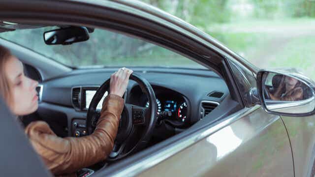A woman in a car checking the mirrors.