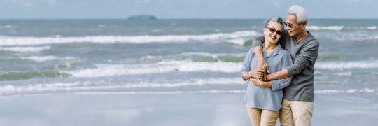 An elderly couple walking on a beach