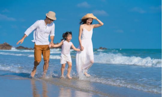 Mum, dad and daughter walking in the surf.