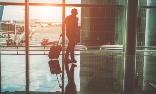 A man walking through an airport with his luggage