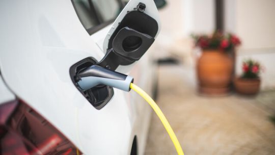 Electric car charging in driveway concept