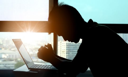 A man sitting at his work desk looking unhappy and stressed