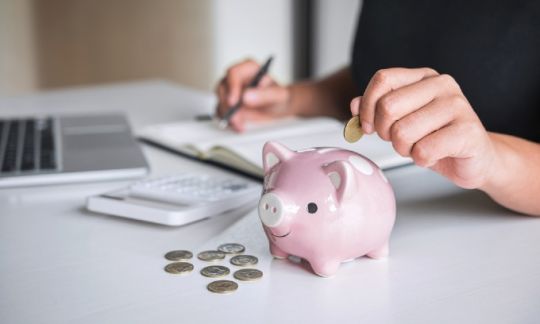 Someone adding money to a piggy bank.