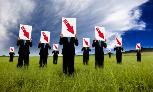 People in suits holding posters with arrows pointing down
