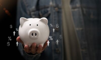 A person in a blue denim jacket holds a white piggy bank.