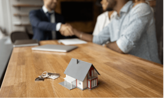 A young couple shake hands with a man who helped them buy their new home with a deposit bond