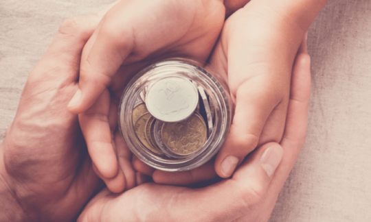 Elderly hands passing on a jar of money to a younger person.