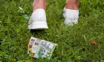A woman walks away, not realising she's left several Australian dollar bills behind her.