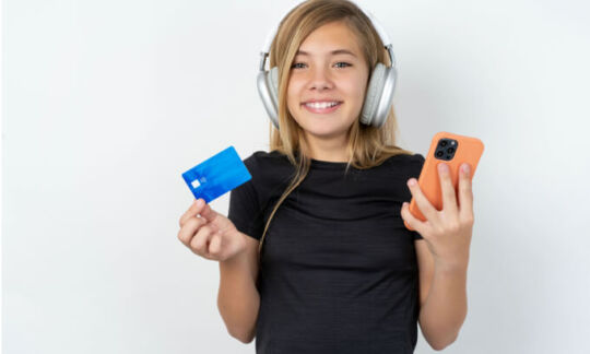 Child holding a debit card and a phone
