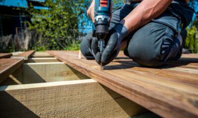 A man uses a drill to create a deck representing deck cost.