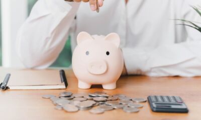 A person drops a coin into a piggy bank representing a default super fund