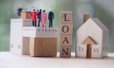 Tiny figurines of people look at a small model house representing guarantor personal loans.