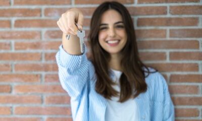 A woman in a blue shirt holds a house key in front of her.