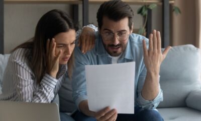 A young couple reviewing a document, looking frustrated and overwhelmed.