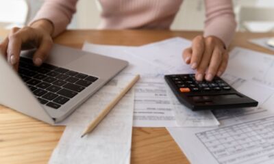 A woman uses a laptop and calculator representing home loan fees.