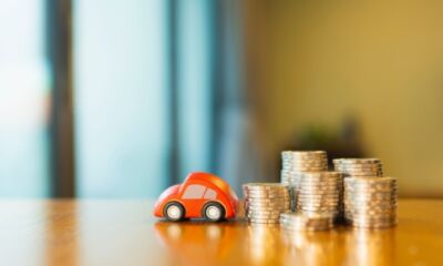 A little red toy car next to a stack of gold coins, representing how much does a car loan cost?