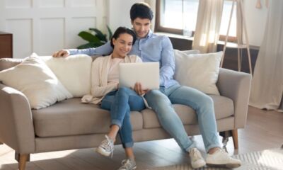 A young couple sits on the couch and look at the cost of home insurance.