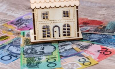 A model wooden house sits on some Australian bank notes representing how to buy a house outright.