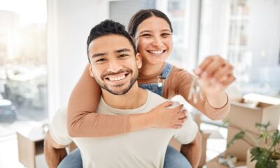 A man gives a woman a piggyback while she holds a set of keys representing how to get a home loan.