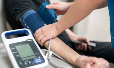 A nurse puts an arm cuff on a patient to check their blood pressure representing life insurance with pre existing conditions.