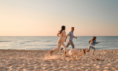 Family running on the beach with dog